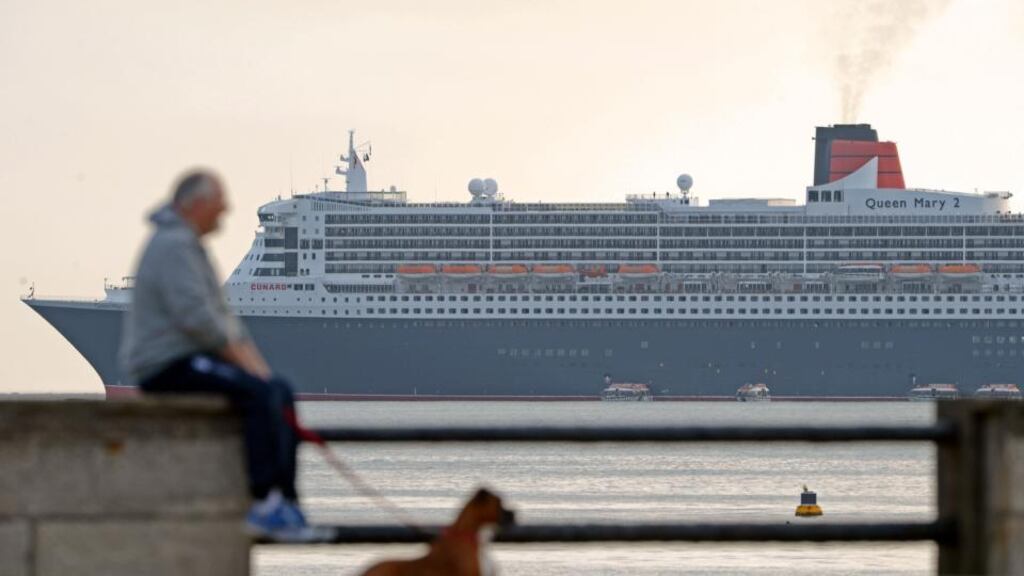 A man and dog look on, asThe Queen Mary II – the flagship vessel of the famous Cunard Line – with 3,000 passengers and several hundred crew members aboard, arrives off Dun Laoghaire Harbour today . Photograph: Eric Luke / The Irish Times