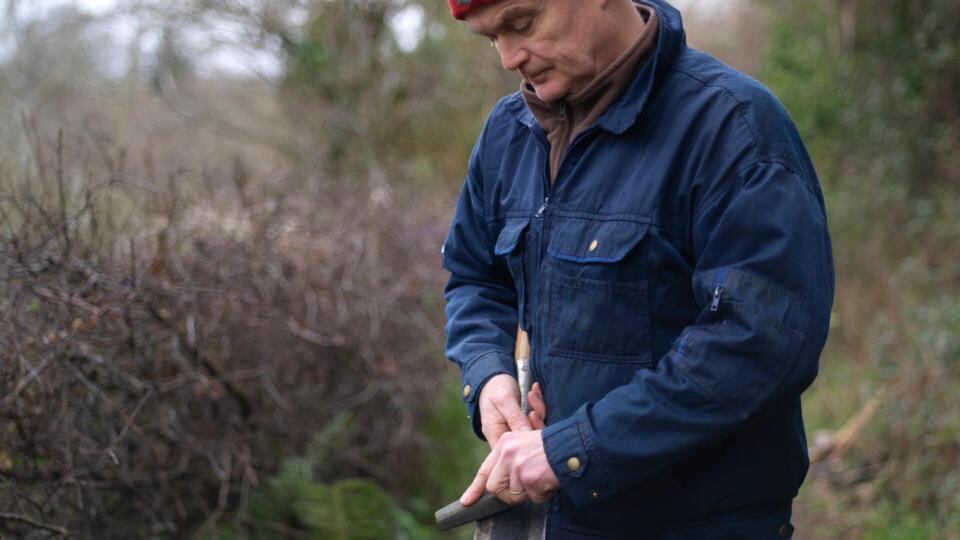 Hedge layer Mark McDowell uses a whetstone to sharpen one of his billhooks. Photograph: Richard Johnston