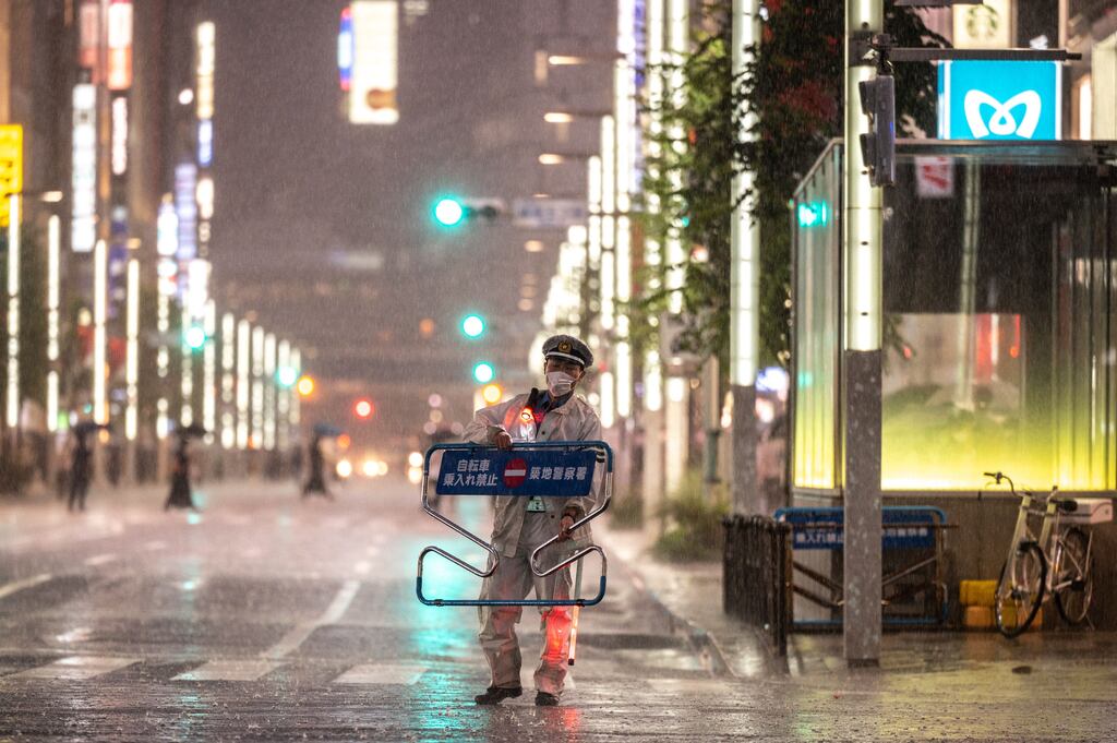 A police officer moves a sign under heavy rain in the Ginza district of Tokyo on Saturday. Photograph: Philip Fong/AFP via Getty Images