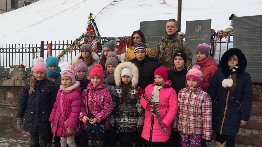 The soldier posing with Tatyana and the children at a memorial to over 100 people killed during Ukraine’s “Revolution of Dignity”