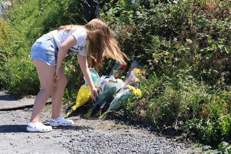 Mick O'Neill's granddaughter, Mya, leaves flowers at the scene at Collinstown lane, Dublin where the award-winning photojournalist was involved in a fatal crash. Photograph: Stephen Collins/Collins Photos