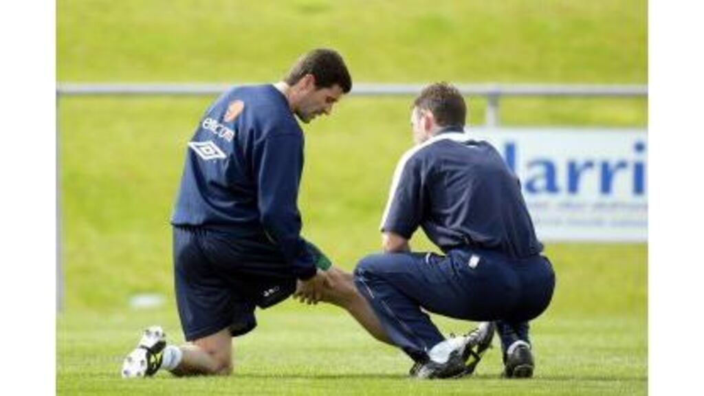 Roy Keane explains his injury problems to Irish team physio Ciaran Murray before withdrawing from the match with Poland.