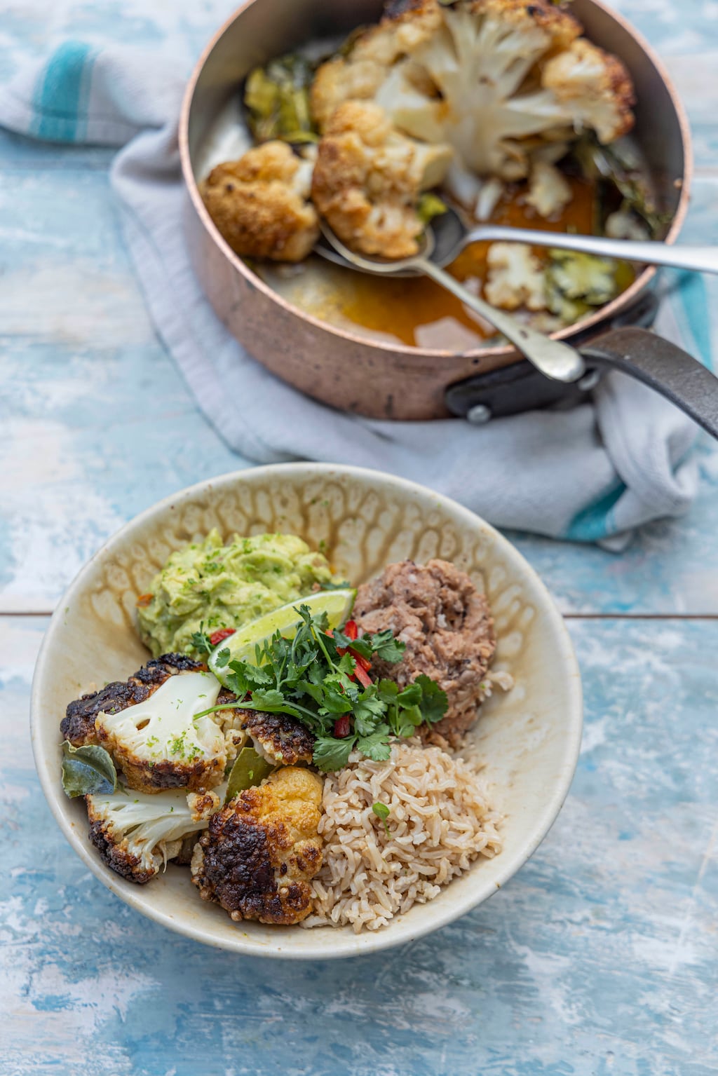 Whole baked cauliflower burrito bowl with refried beans and guacamole. Photograph: Harry Weir
