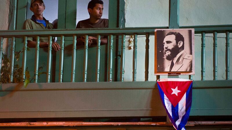 Residents stand next to an image of the late Cuban leader Fidel Castro and a Cuban Flag in Havana, Cuba over the weekend. Photograph: Ramon Espinosa/AP Photo
