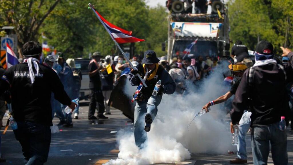 An anti-government protester kicks away a teargas canister during clashes with police near the metropolitan police headquarters in Bangkok. Photograph: Chaiwat Subprasom/Reuters