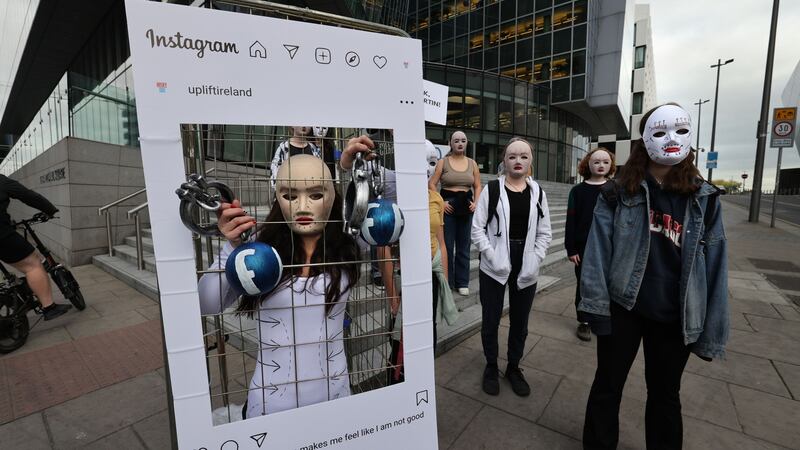 A group of young people stand outside Meta headquarters, previously known as Facebook, in Dublin, wearing masks resembling photo filters used on social media. Photograph: Dara Mac Dónaill