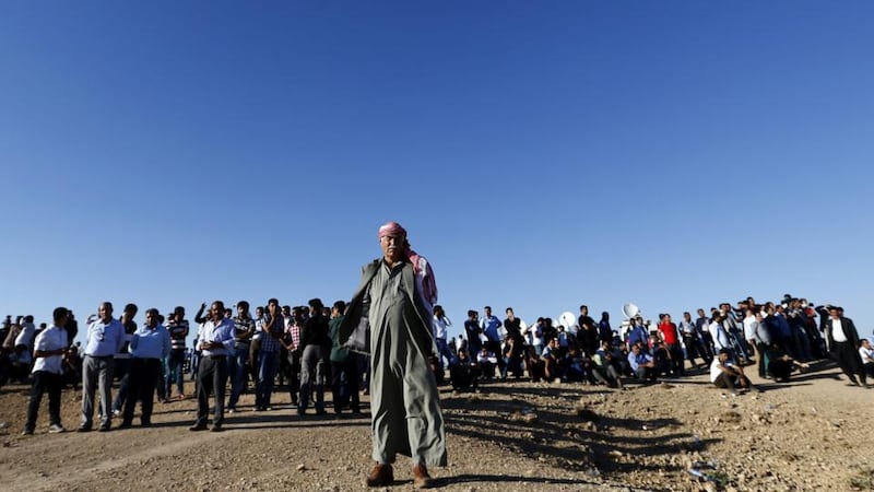 Kurdish people watch an Islamic State attack on Kobani city near Turkish-Syria border. Kurdish forces are battling to hold the Syrian town from the advancing insurgents. Photograph: Sedat Suna/EPA.