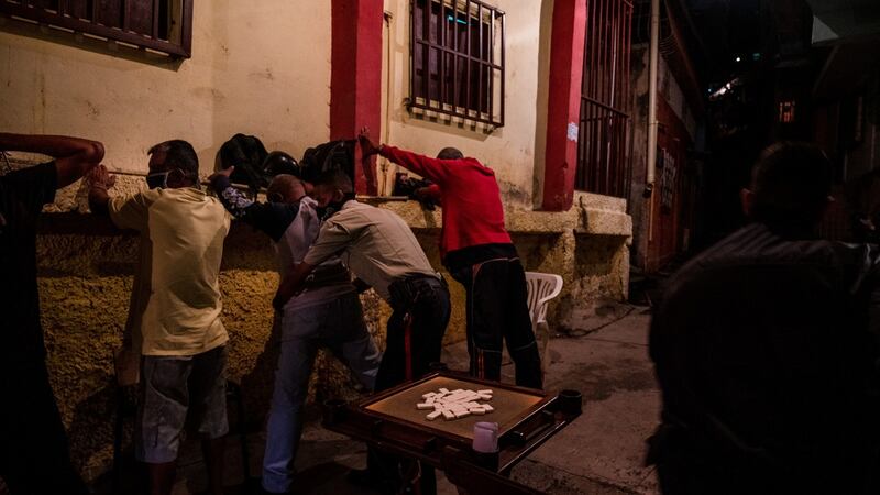 Officers in Caracas search a group of men who were playing dominos in the street in violation of quarantine measures on August 6th. Photograph: Adriana Loureiro Fernandez/The New York Times