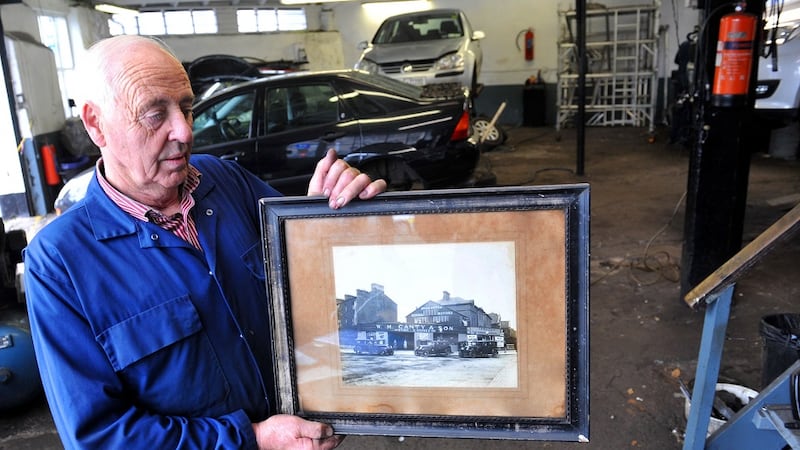 Martin Canty is holding a black and white photo from the late 1920s which includes his grandfather Bill Canty, his father Archie Canty and two aunts at the family business premises. Pictures: Larry Cummins
