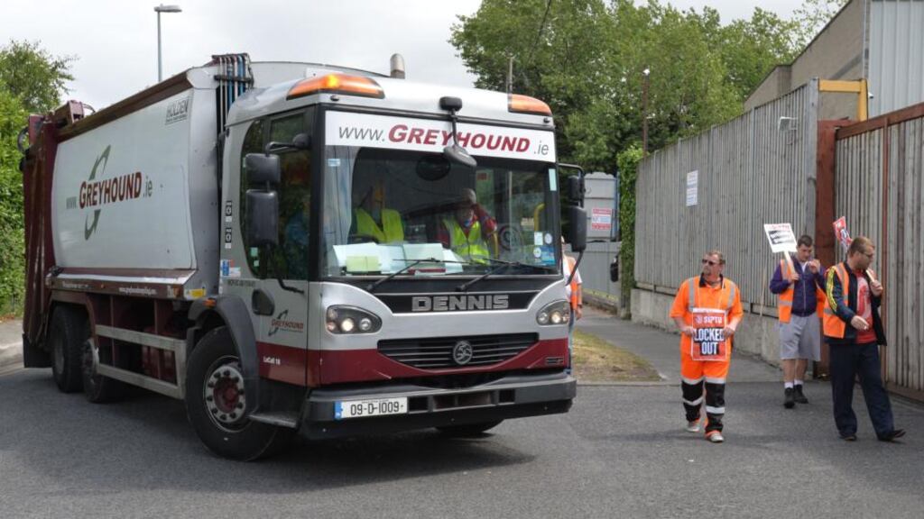 Workers on strike at the Greyhound Recycling and Recovery buildings at Knockmitten Lane protest as replacement workers operate the waste collection trucks yesterday. Photograph: Alan Betson