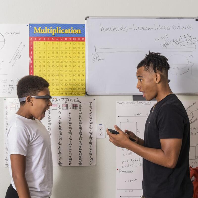 Esaïe Prickett, wearing Google Glass, practices facial expressions with his brother Morgan at their home. Photograph: Cayce Clifford/The New York Times
