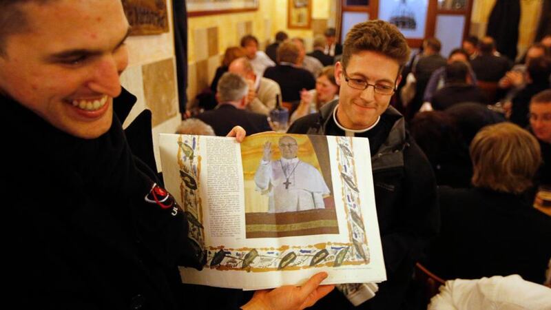 Seminary students from Australia hold a special edition of the Vatican newspaper Osservatore Romano to diners from Ireland, in Rome yesterday. Jorge Mario Bergoglio of Argentina was elected in a surprise choice to be the new pope. Photograph: Chris Helgren/Reuters