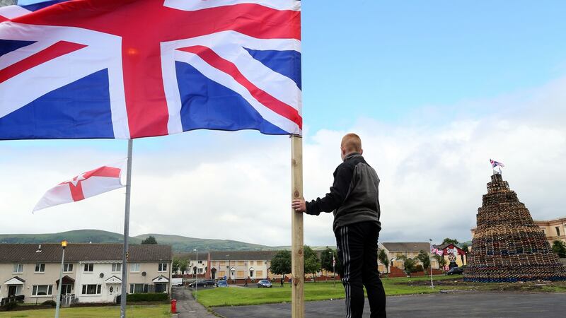 A boy balances on a fence as Union flags flutter in the breeze beside one of the largest 11th night bonfires in the lower Shankill road area of Belfast,  on July 11th, 2016. Photograph:  Paul Faith / AFP via Getty Images)