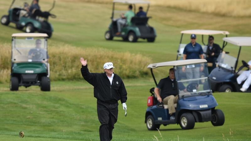 Trump waves at protestors while playing at Turnberry in 2018. Photo: Leon Neal/Getty Images