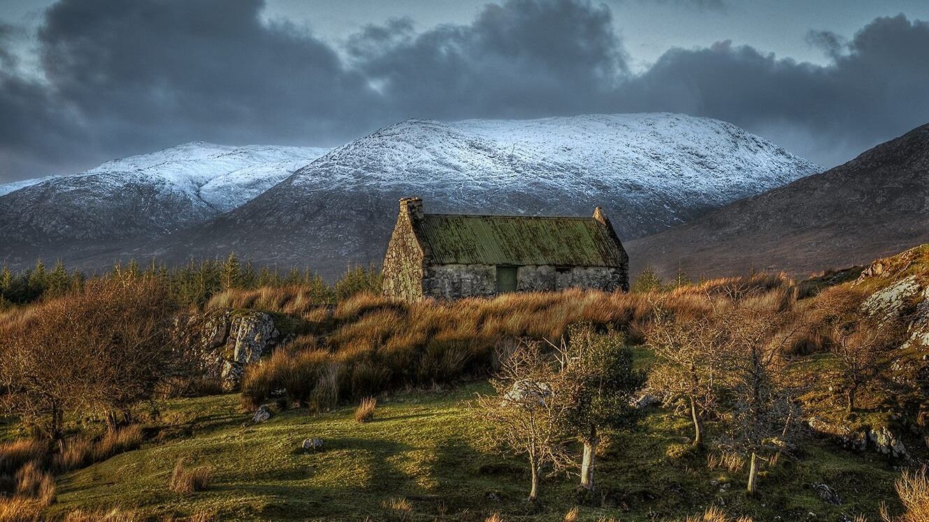 A cottage in Connemara, Co Galway with snow topped hills in the background. Photograph: Trevor Dubber