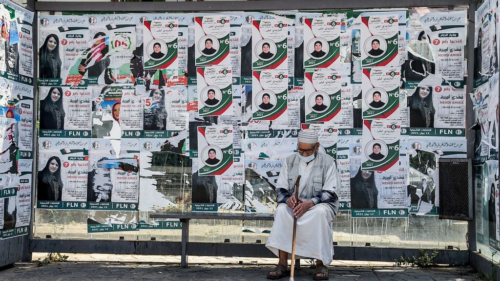 A man sits at a bus stop covered with posters of a candidate of the Future Front political party in Algiers on Friday. Photograph: Ryad Kramdi/AFP via Getty Images