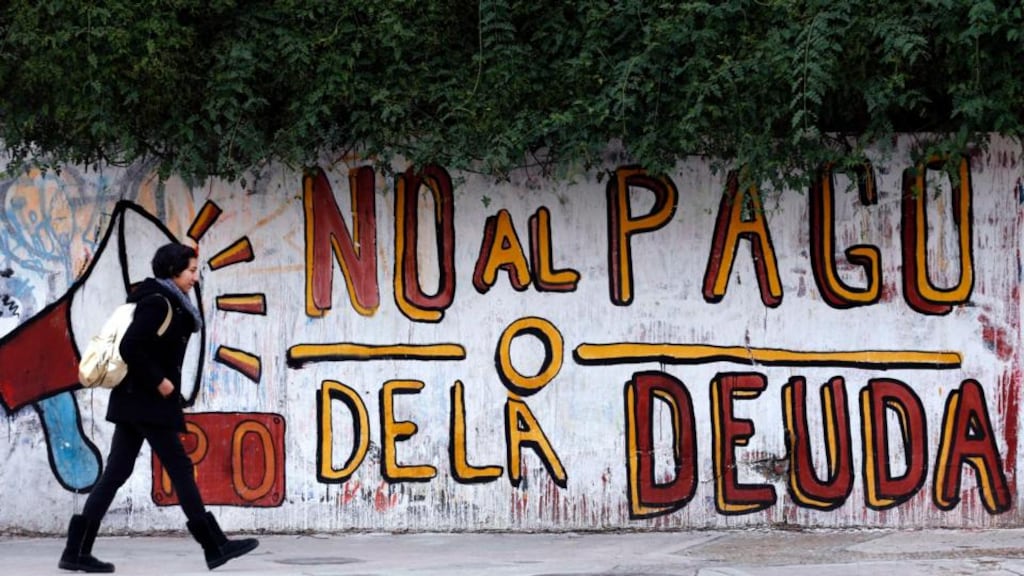 A woman walks past a graffiti that reads “No to the debt payment” in Buenos Aires. Photo: Reuters