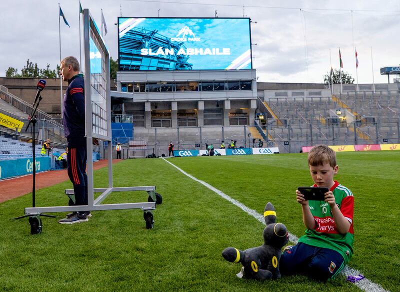 Mayo manager James Horan interviewed as his son Eoghan plays on a phone after the All-Ireland final. Photograph: James Crombie/Inpho