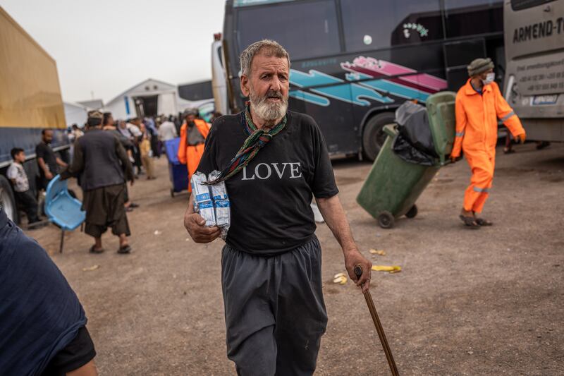 Mohammad Akhundzada, a construction worker in Iran for decades, carries biscuits provided by aid groups to his family in the border town of Islam Qala, Afghanistan. Photograph: Jim Huylebroek/The New York Times