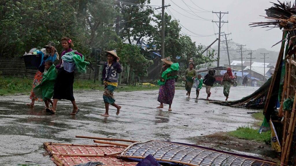People carry their belonging as they walk near damaged houses in Sittwe, Rakhine State, western Myanmar, on Tuesday. Photograph: Nyunt Win/EPA