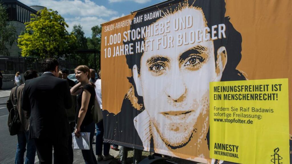 Protesters stand in front of a placard reading ‘1,000 lashes and 10 years of prison for a blogger’ and ‘Freedom of speech is a human right’ which they placed in front of the Saudi-Arabian embassy in Berlin. Photograph: Paul Zinken/EPA
