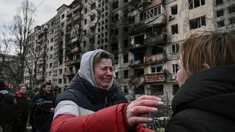 A woman reaches to embrace another outside destroyed apartment blocks after shelling in the northwestern Obolon district of Kyiv. Photograph: Aris Messinis