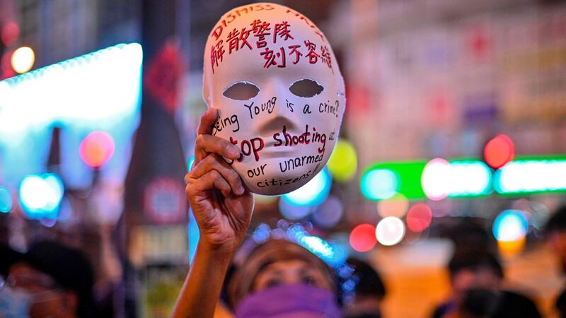 A woman holds a mask with slogans written on as protesters gather outside Mong Kok police station in Hong Kong on Saturday. Photograph: Philip Fong/AFP