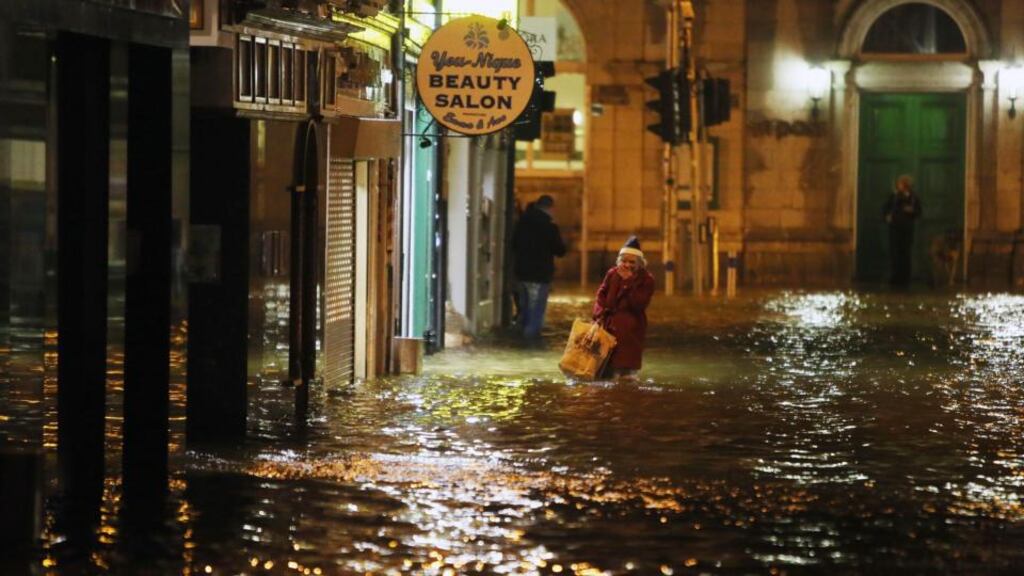A woman walks through flood water in Cork city in February. The cost of claims arising out of last winter’s bad weather has been more than expected, insurer FBD has said. Photograph: Niall Carson/PA Wire