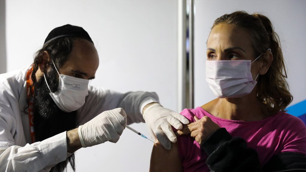 A  woman receives a Covid-19 vaccine shot from a male nurse  in Jerusalem, Israel. The vaccine is administered at 350 locations, ranging in size from local healthcare settings to large sports stadiums. Photograph: Abir Sultan/EPA
