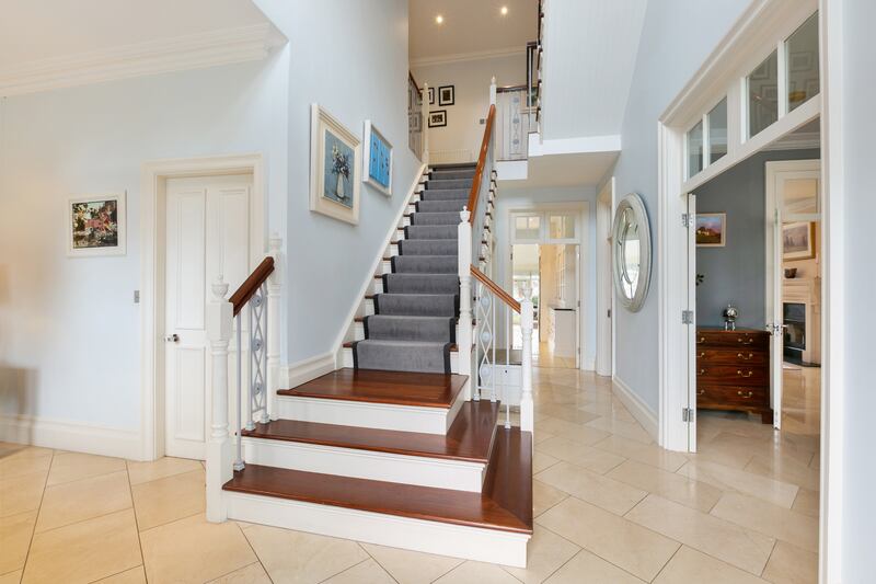 The entrance hall has a marble floor and triple-height ceiling with large windows