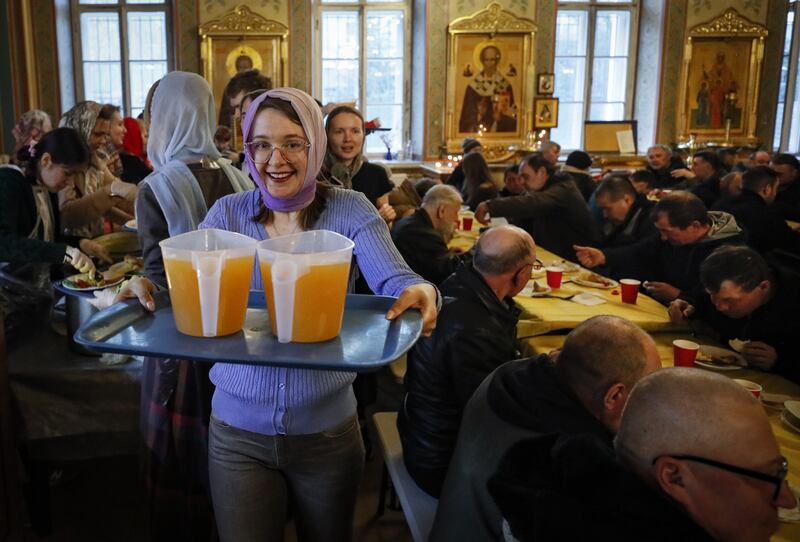 A volunteer serves juice during an Easter dinner hosted for the homeless in the Orthodox Church in Moscow, Russia Photograph: Yuri Kochetkov/EPA