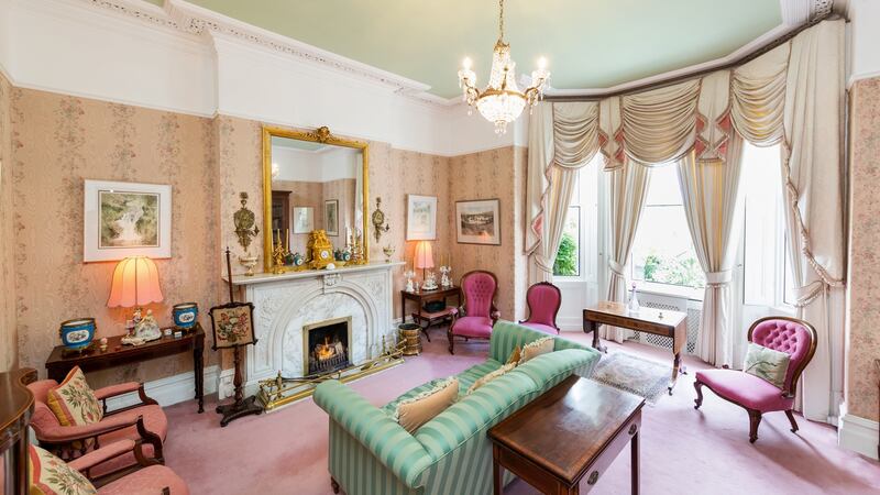 The living room which is light filled with wide bay windows.