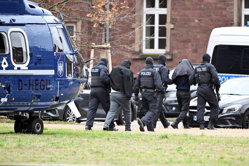 Two people are led from a helicopter to a car by police officers at a helipad in Karlsruhe, Germany, on Friday. Photograph: Uli Deck/dpa via AP