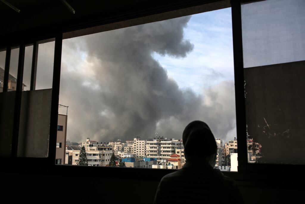 A woman watches from an apartment in Gaza City as smoke rises from Israeli air strikes on Wednesday. Photograph: Samar Abu Elouf/The New York Times