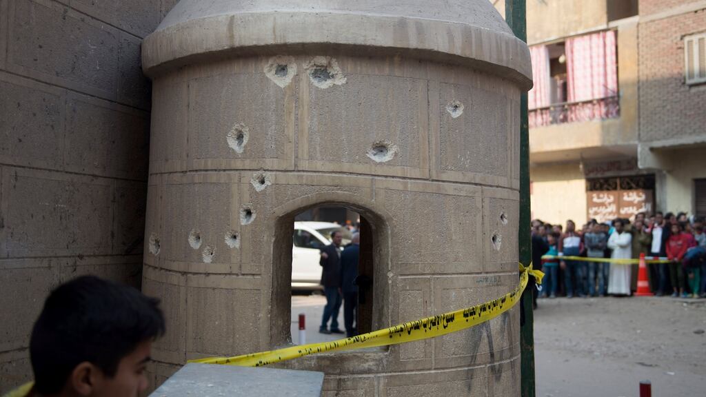 People stand near construction with bullet holes outside Mar Mina church following an attack on the church in the district of Helwan, southeastern Cairo, Egypt, 29th December 2017. Photograph: EPA/MOHAMED HOSSAM