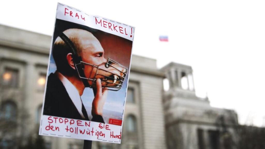 A poster depicting Vladimir Putin with a muzzle says “Mrs Merkel! Stop the mad dog”, seen at a demonstration outside the Russian embassy in Berlin yesterday. Photograph: Kay Nietfeld/EPA