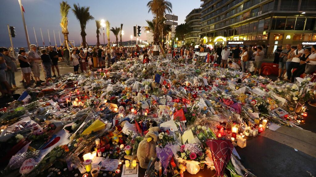 People standing in front of flowers, candles and messages laid at a makeshift memorial in Nice in tribute to the victims of the deadly attack on the Promenade des Anglais seafront which have now killed 85 people. Photograph: Valery Hache/AFP/Getty Images