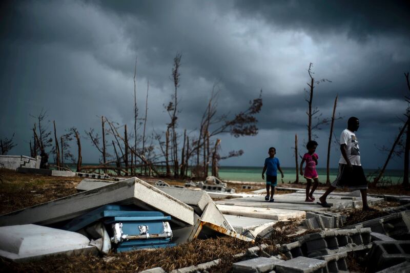 People walk next to a shattered and water-filled coffin  exposed to the elements in the aftermath of Hurricane Dorian, at the cemetery in Mclean’s Town, Grand Bahama on Friday. Photograph: Ramon Espinosa/AP