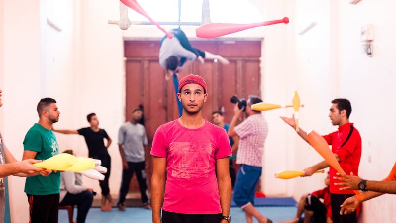 Murad Marosh holds very still as his teammates pass juggling clubs either side of him.