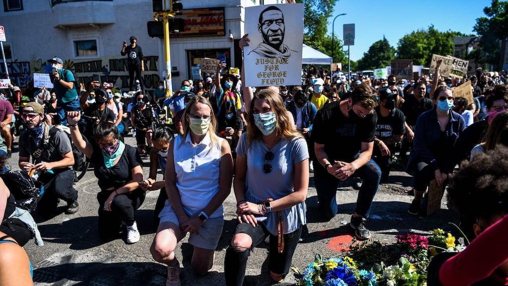 Protestors in Minneapolis kneel down as they protest at the makeshift memorial in honour of George Floyd, who died while in custody of the Minneapolis police. Photo: Chandan Khanna/AFP via Getty Images