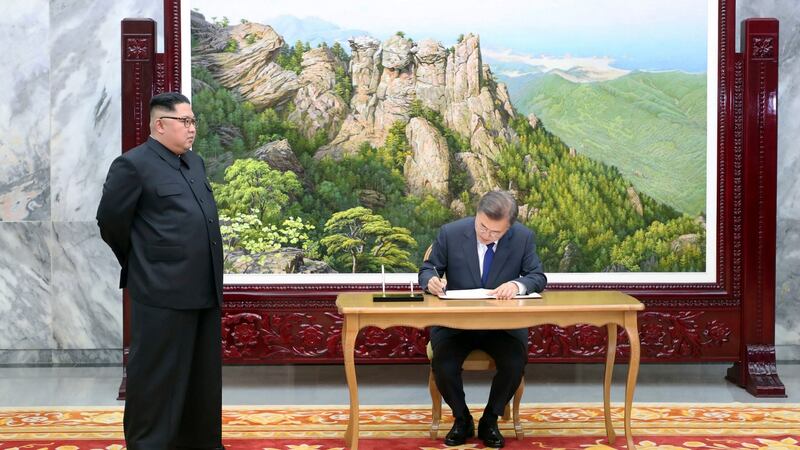 South Korean president Moon Jae-in writes on a visitor’s book as North Korean leader Kim Jong-un looks on in Panmunjom. Photograph: South Korea Presidential Blue House/Yonhap via AP