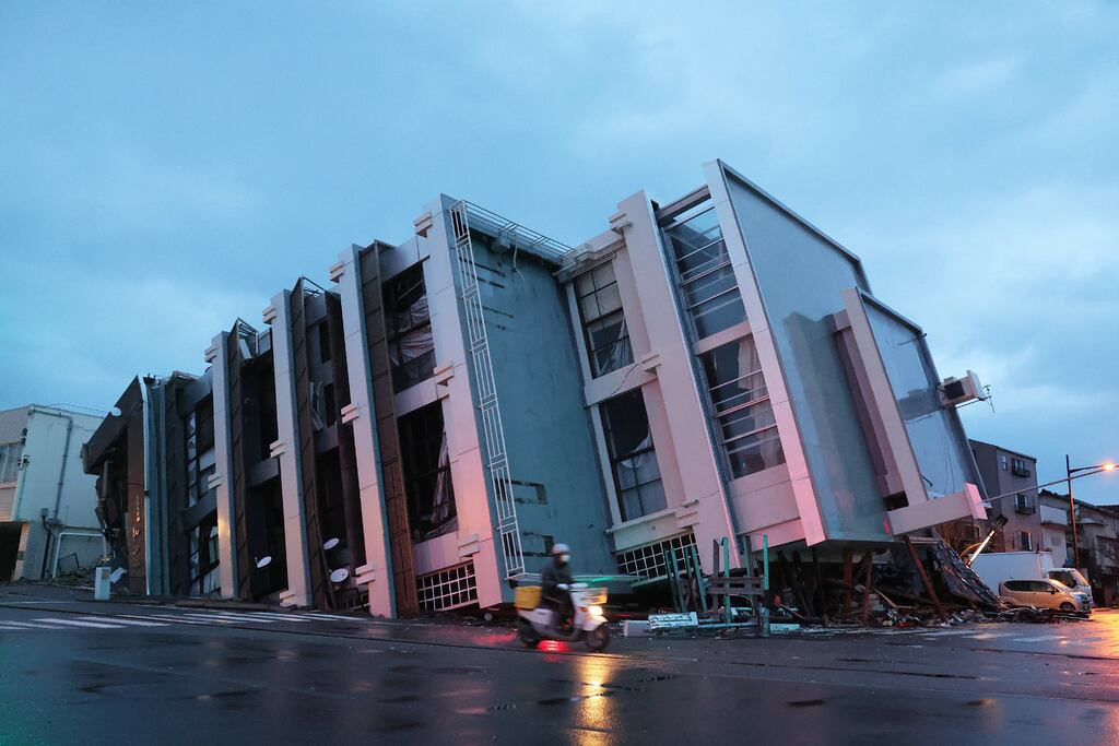 A man on a scooter passes a collapsed multistorey building in the city of Wajima, Ishikawa prefecture, on Wednesday after a major earthquake struck the Noto region on New Year's Day. Photograph: Jiji Press/AFP via Getty Images