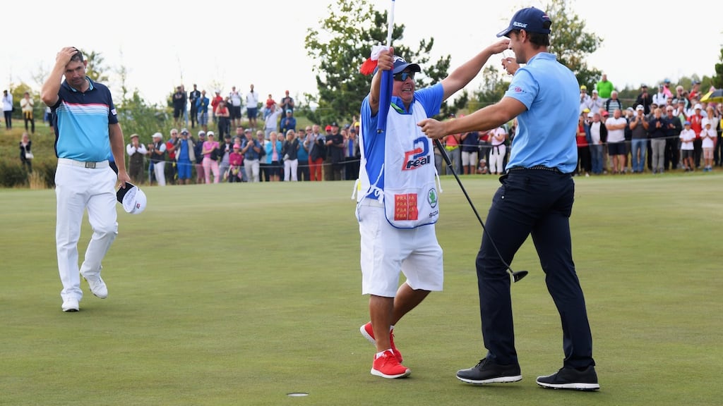 Andrea Pavan of Italy victory with his caddie on the 18th green as Padraig Harrington of Ireland looks on. Photograph: Getty Images