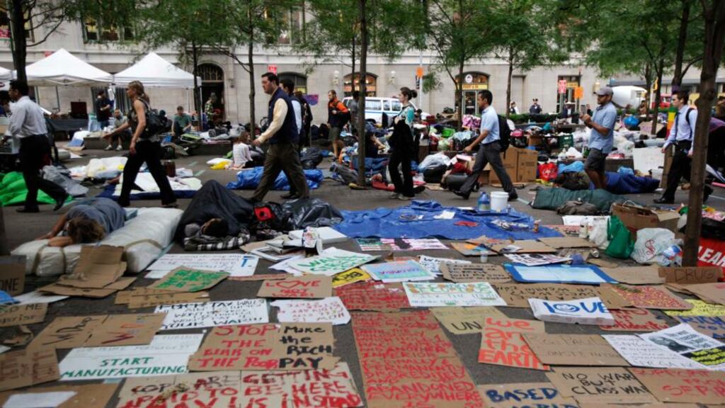 Morning commuters walk past Occupy Wall Street campaign protesters sleeping  near Wall Street in New York in 2011