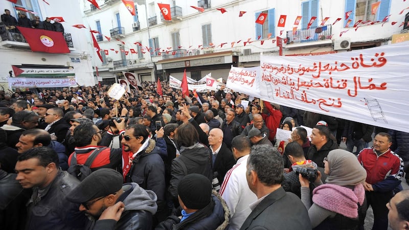 Tunisian people march with national flags during a rally to mark seven years since revolution in Tunis on Sunday. Photograph: Hassene Dridi/AP
