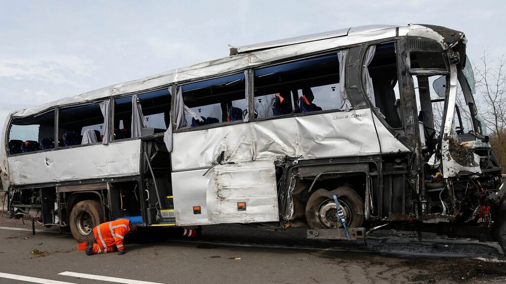 Workers inspect the wreckage of a  bus, which  crashed through the guardrails of a  motorway near Antwerp in Belgium this morning and plunged down a ravine, killing five people. Photograph: Francois Lenoir/Reuters.