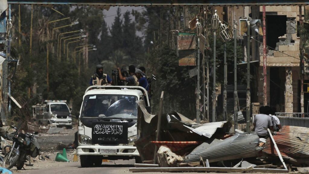 Free Syrian Army fighters ride on a pick up truck decorated with an Islamist flag along a damaged street in Deir al-Zor. Photograph: Khalil Ashawi/Reuters
