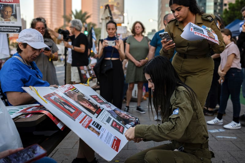 An Israeli soldier tapes a photo of her friend Ron Sherman, who is among the 203 people believed have been kidnapped by Hamas militants, to a poster during a demonstration in Tel Aviv, Israel, on Friday. Photograph: Tamir Kalifa/The New York Times