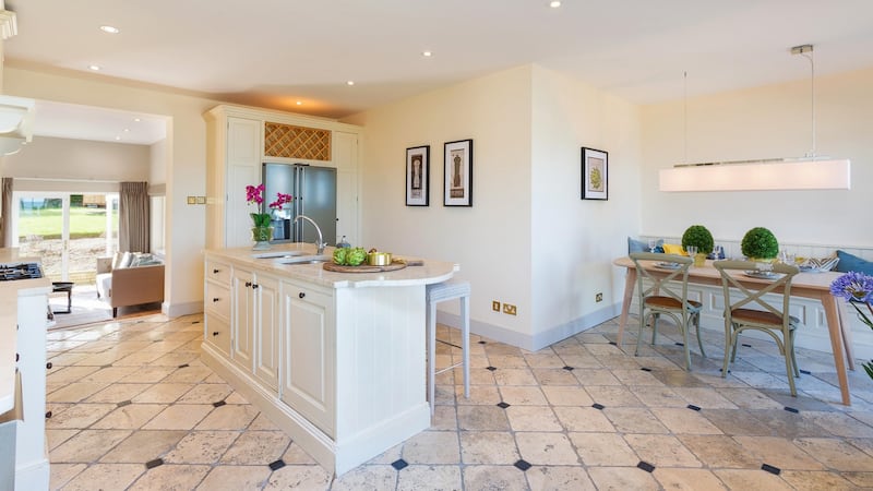 The large fitted kitchen from Design House in Dalkey has cream units, a stone tiled floor and polished stone countertops and island unit