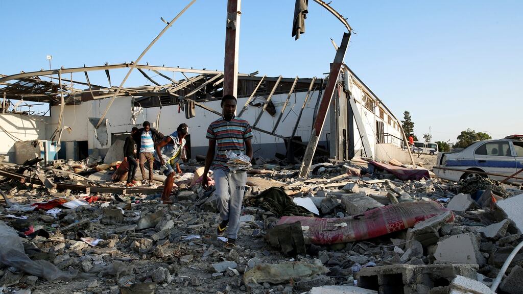 Migrants carry the remains of their belongings from among rubble at Tajoura  detention centre in Tripoli on Wednesday, after it was hit by an air strike. Photograph: Ismail Zitouny/Reuters